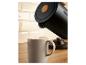 Bouilloire noire versant de l'eau dans une tasse sur un comptoir en bois.