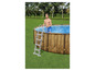 Een man die in een rond, houten zwembad stapt met een ladder.