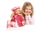Een meisje met een roze jurk en een pop in een roze jas.