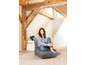 Een vrouw zit op een grijze fauteuil in een modern interieur.