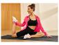 Vrouw op yogamat die rekt, gekleed in zwarte sportkleding en een roze jasje.