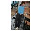 Une femme portant un pull bleu, un pantalon noir et des baskets blanches travaille sur un ordinateur portable.