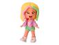 Een poppenfiguur met roze jas, groene shorts en wit-roze schoenen.