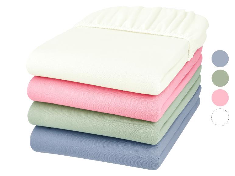 Pile de draps-housses aux couleurs pastel : blanc cassé, rose, vert menthe et bleu.
