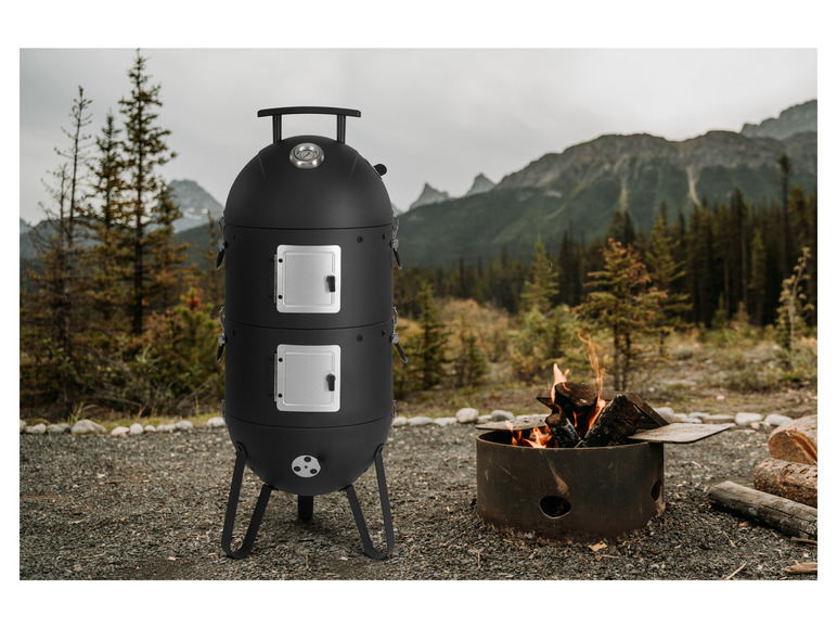Un fumoir noir avec deux portes, à côté d'un feu de camp dans les montagnes.