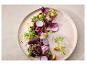 Verse gemengde groene salade met radijsjes, spruiten, croutons en eetbare bloemen op een bord.
