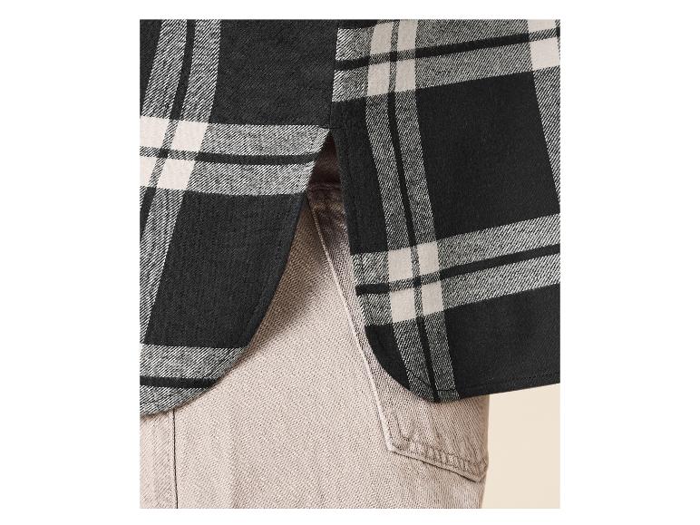 Chemise à carreaux noire et blanche avec ourlet arrondi, associée à un pantalon clair.