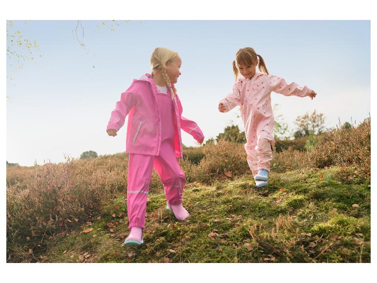 Deux filles en cirés roses et bottes en caoutchouc jouant en extérieur.
