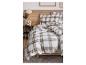 Slaapkamer met geruit beddengoed, houten hoofdbord en nachtkastje met decoraties.