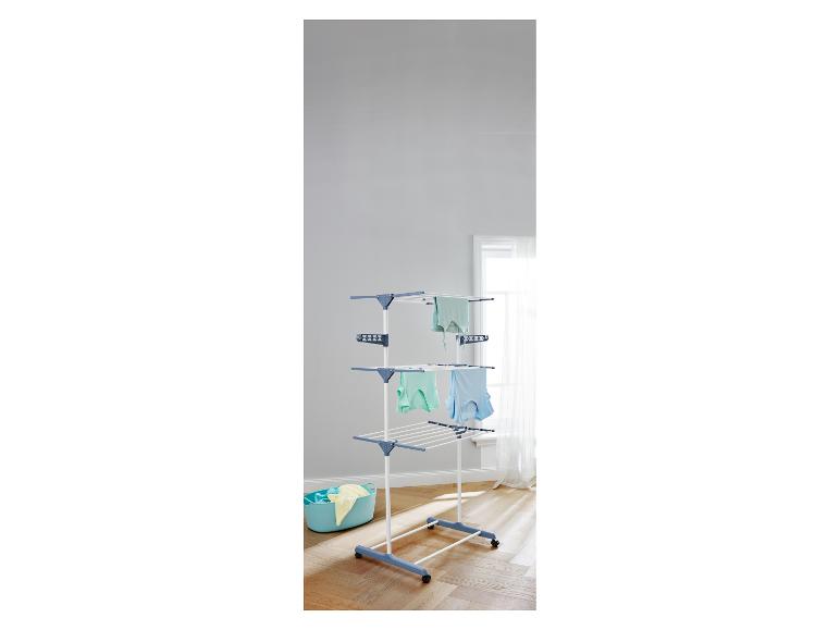 Wit en blauw droogrek met drie niveaus en een blauwe wasmand.
