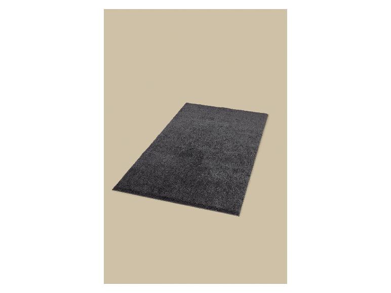 Donkergrijze badmat op een beige achtergrond.