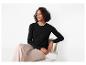 Femme en cardigan noir et pantalon beige assise sur une chaise.
