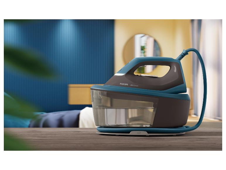 Fer à vapeur sur une table en bois dans une chambre avec un mur bleu et un miroir jaune.