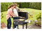 Een paar barbecuet in de achtertuin met een barbecue met grillroosters en zijtafel.
