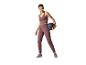 Femme en tenue de sport violette, tenant un ballon lesté noir.