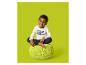 Lachende jongen in wit 'TEAM VALENTINE' shirt en donkerblauwe broek, zittend op een groene poef.