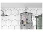 Een zwart draadrek met L'Occitane producten in een badkamer met witte hexagon tegels.
