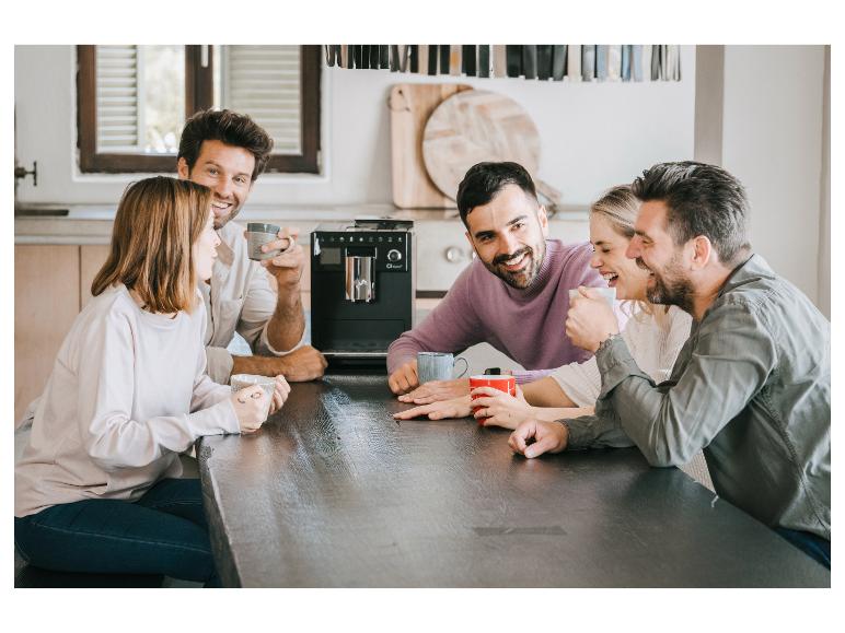 Amis savourant café et conversation autour d'une table avec une machine à café.