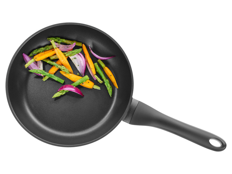 Une poêle noire avec des asperges, des carottes et des oignons rouges grillés.