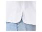 Détail d'une chemise blanche avec fente et ourlet arrondi, portée avec un jean bleu.