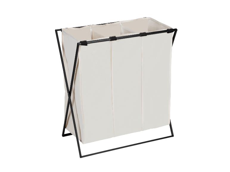 Een beige linnen wasmand met drie compartimenten en een zwart metalen frame.