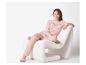 Jeune femme assise sur une chaise blanche, vêtue d'un pyjama rose à pois.