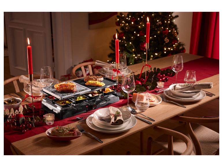 Raclette grill met steen- en grillplaat op een kersttafel met decoraties.