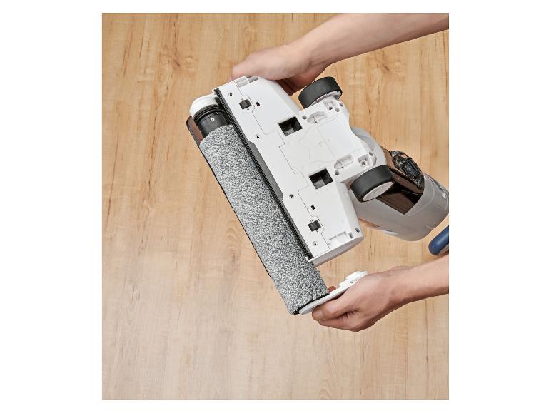Mains tenant le dessous d'un aspirateur sans fil avec un rouleau de nettoyage.