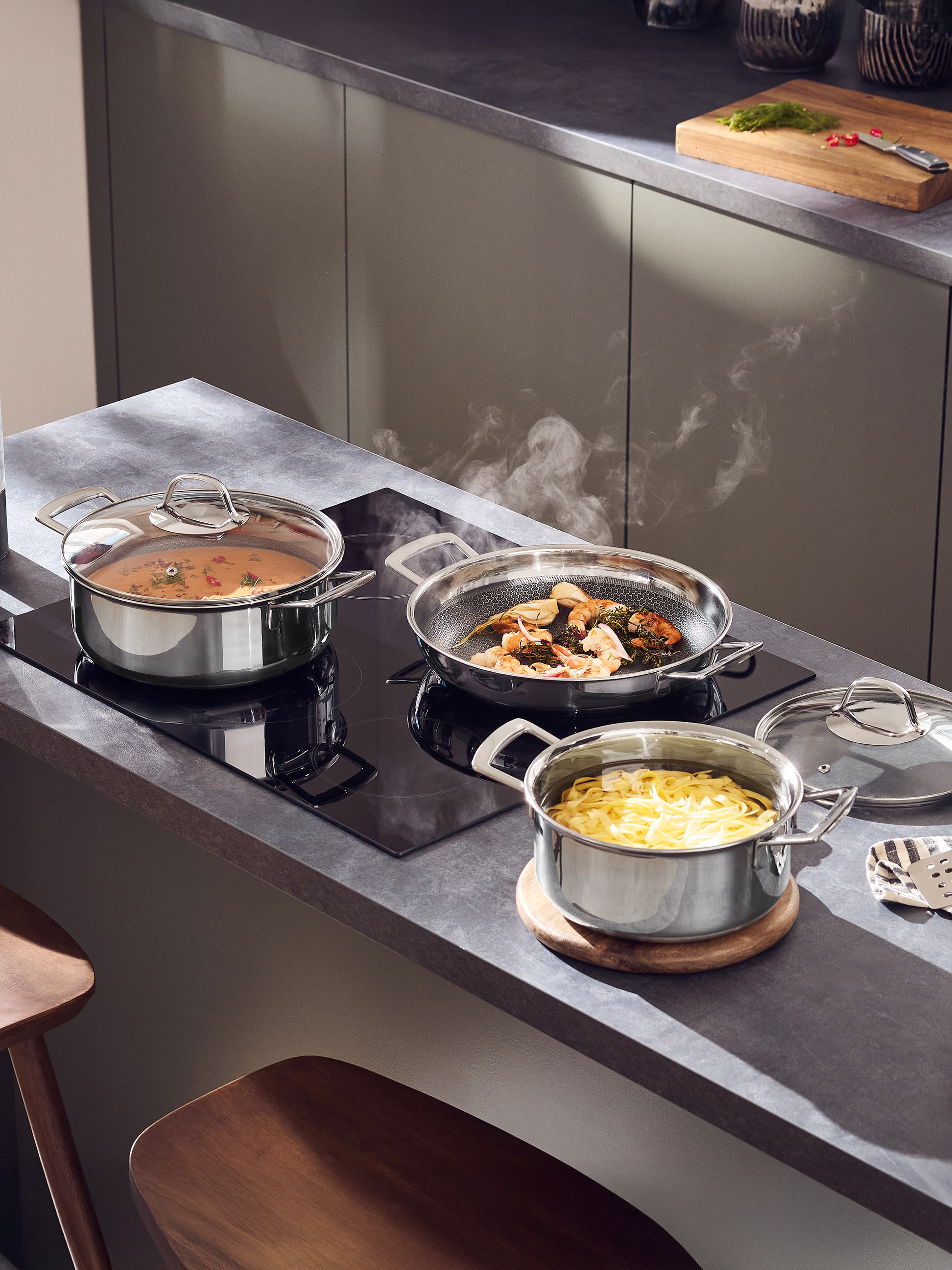 Roestvrijstalen potten en pannen met etenswaren die koken in een moderne keuken.