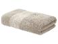 Serviette de bain beige pliée avec un motif décoratif de feuilles.