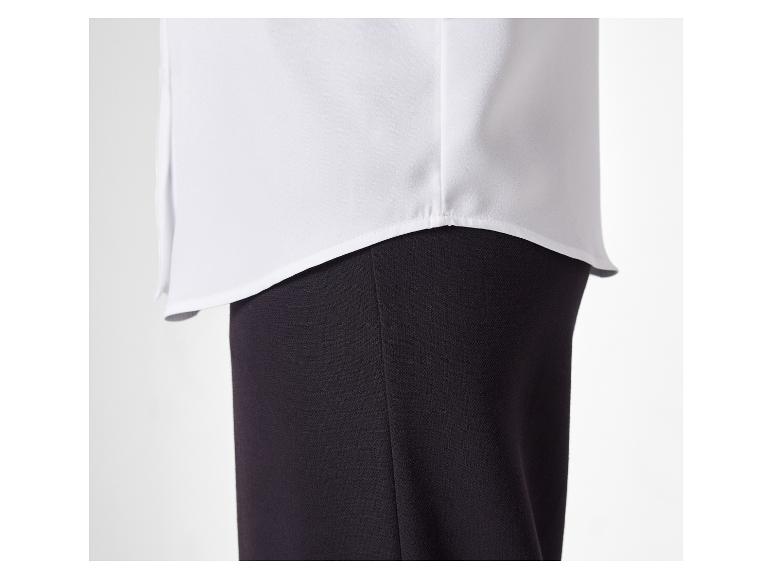 Wit overhemd met lange mouwen en zwarte broek.