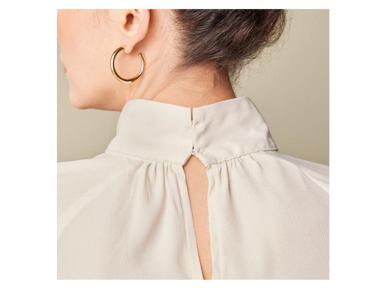 Een vrouw draagt een witte blouse met een open rug.