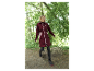 Femme portant un long manteau softshell bordeaux Icepeak marchant sur un sentier boisé.