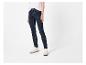 Femme en t-shirt blanc et jean skinny bleu foncé, baskets beiges et chaussettes blanches.