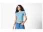 Femme souriante en t-shirt côtelé bleu clair et jean.