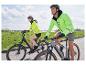 Twee personen fietsen, gekleed in felgele veiligheidsjacks.