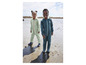Deux enfants en salopettes vertes et menthe sur la plage.