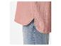 Détail d'une chemise en mousseline rose avec ourlet arrondi et jean bleu.