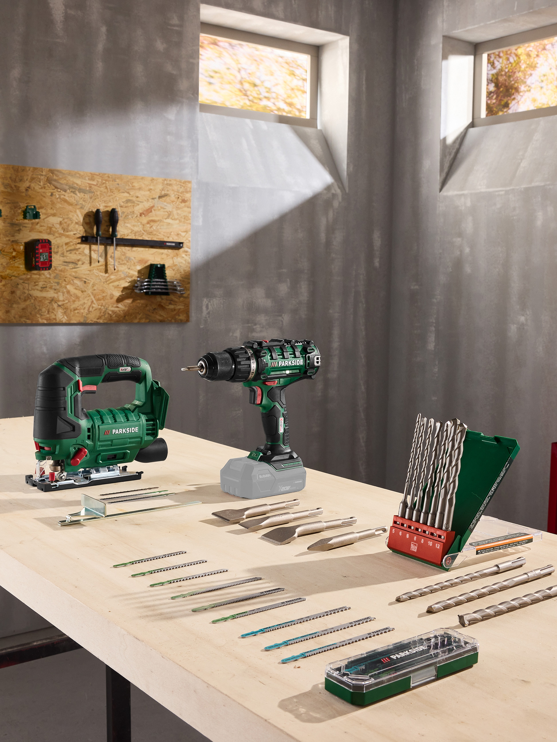 Decoupeerzaag en accuboormachine met diverse accessoires op een houten werkbank.