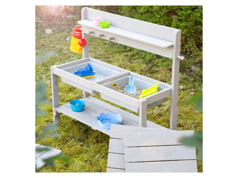 Houten zand- en watertafel met kleurrijke accessoires in een tuin.