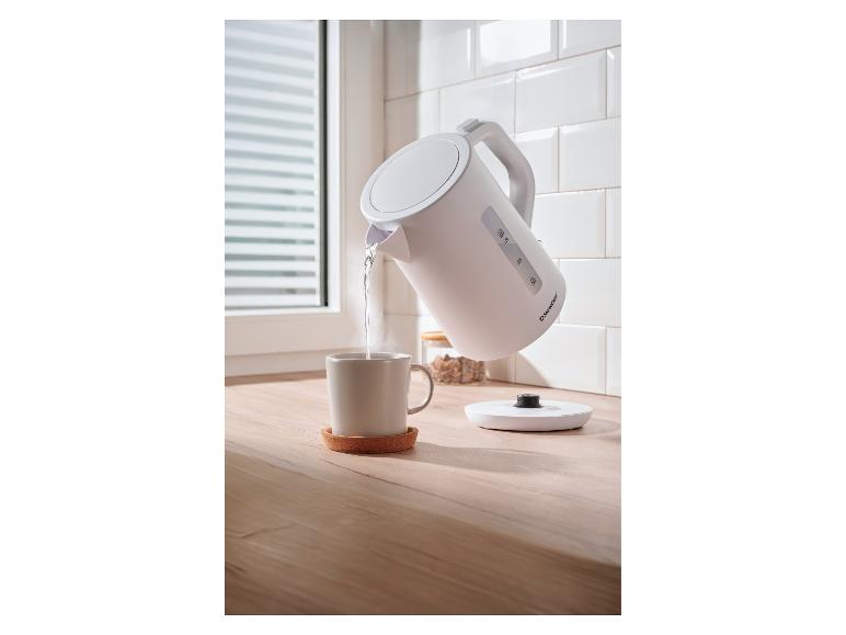 SilverCrest waterkoker giet heet water in een mok op een houten aanrecht.
