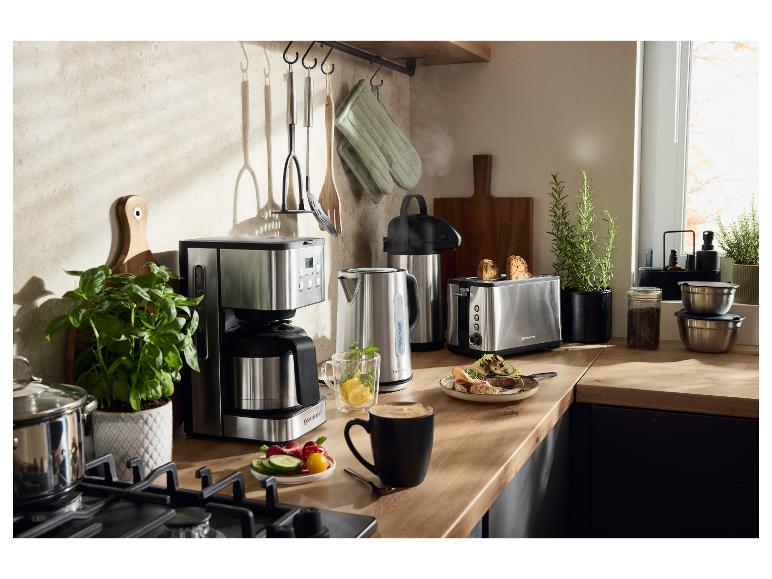 Roestvrijstalen keukenapparatuur, waaronder een koffiezetapparaat, waterkoker en broodrooster, op een houten aanrecht.