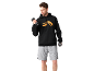 Homme en sweat à capuche noir avec logo orange et short gris, tenant des haltères.