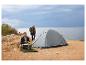 Tente de camping Crivit et femme préparant un repas en plein air au bord de la mer.