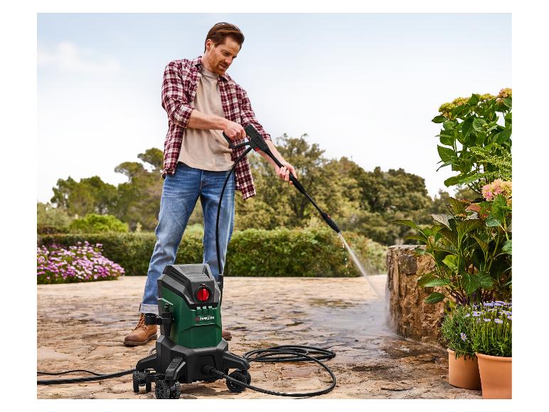 Een man gebruikt een Parkside hogedrukreiniger om een terras schoon te maken.