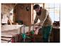 Un homme utilise des serre-joints pour fixer une planche de bois sur un établi dans un atelier.