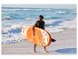 Homme en gilet de sauvetage portant un paddleboard orange sur une plage de sable avec des vagues.