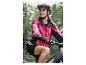 Een vrouw in een roze fietsjack en een zwarte helm op een e-bike in het bos.