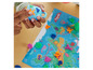 Un enfant joue avec de la Play-Doh, une valise bleue et une carte du monde.