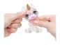 Deux mains pressent un jouet licorne transparent et pailleté avec de grands yeux et une corne dorée.
